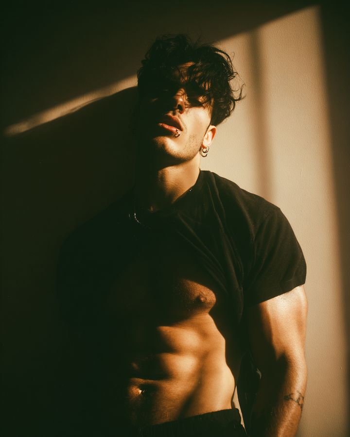 A man in a black T-shirt in warm window light