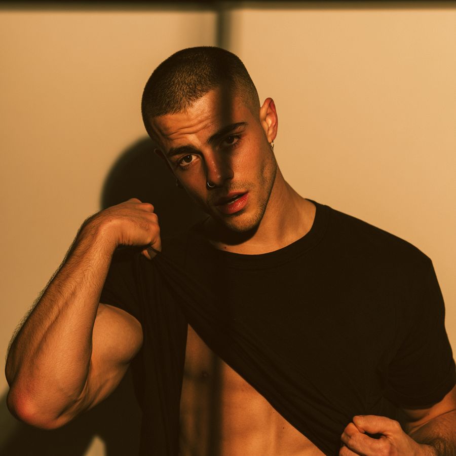 A man in a black T-shirt against an orange wall