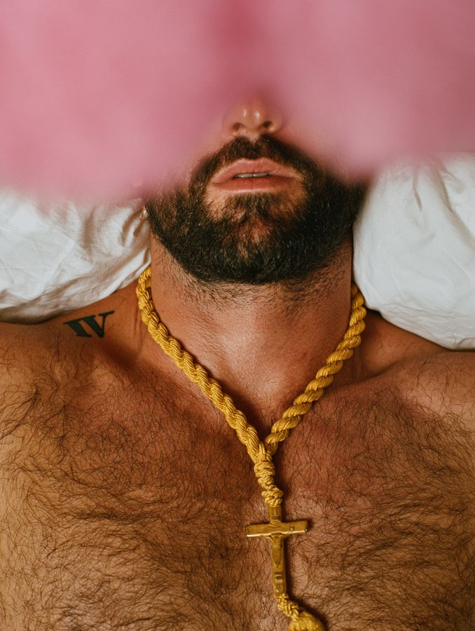 A man with a gold chain against a pink background