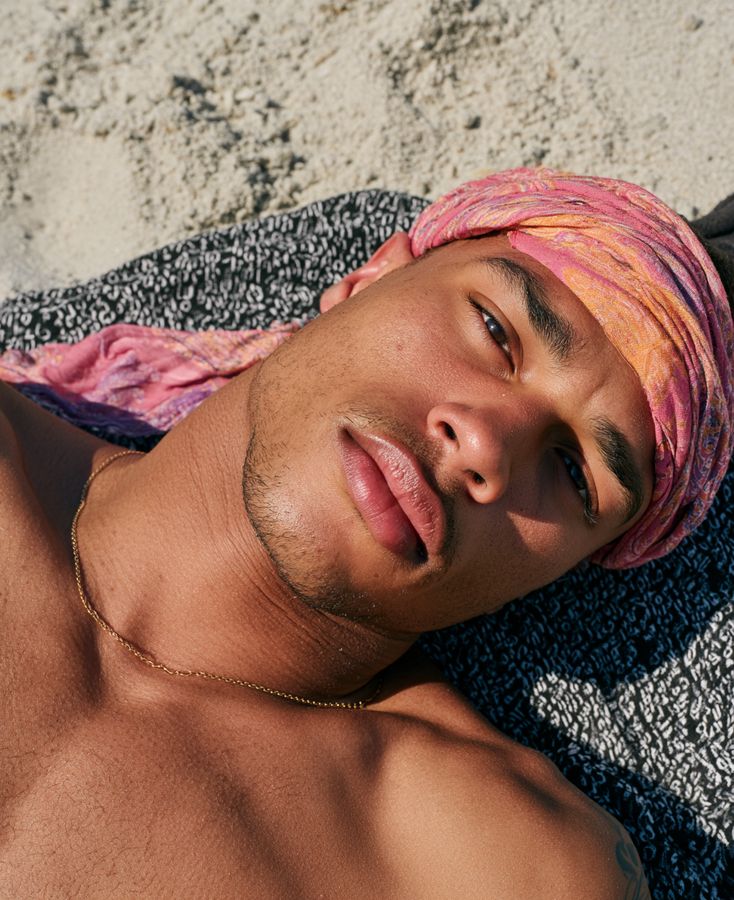 A man with dyed hair lying on sand