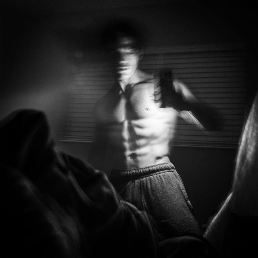 A man lit by window blinds, in black and white