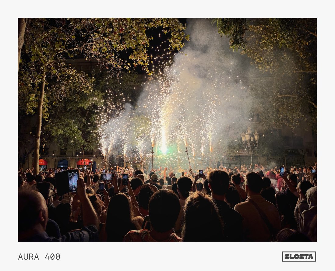 Fireworks bursting over a crowd at night, framed with SloSta's AURA 400 film stock