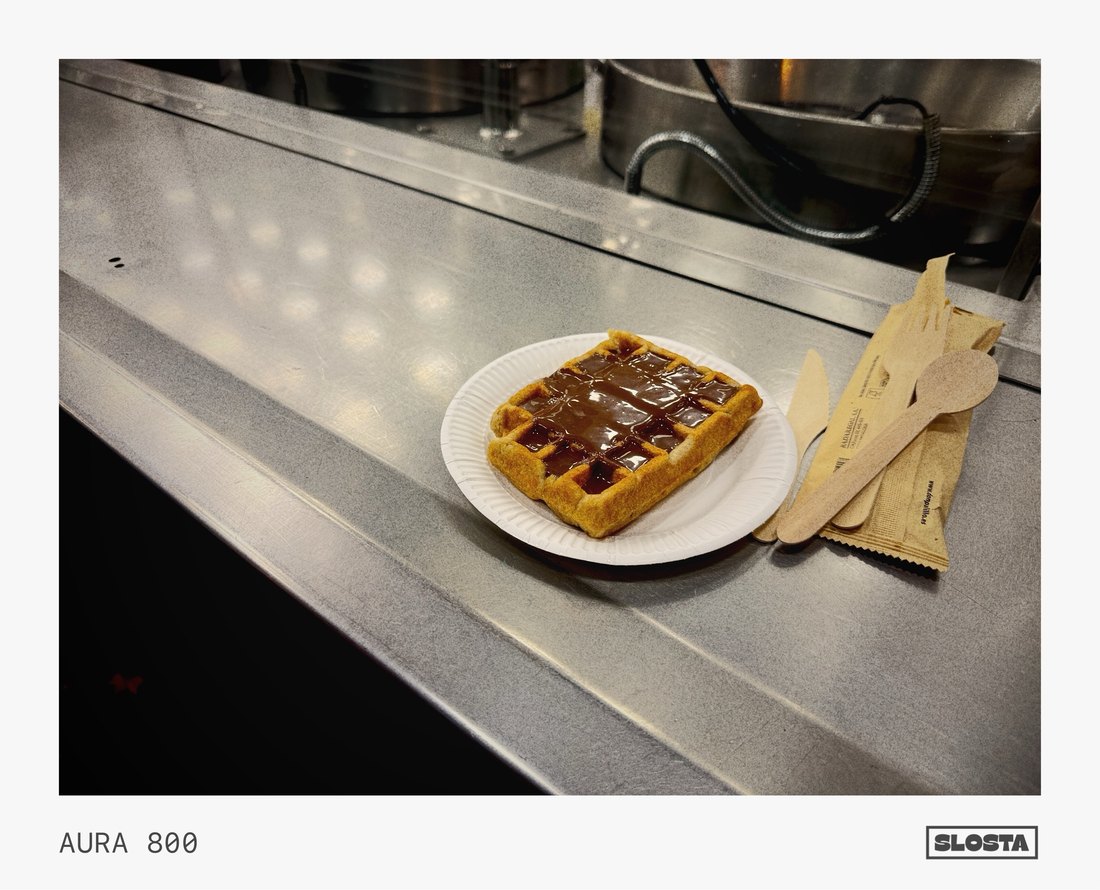 A waffle on a plate at a café table, framed with SloSta's AURA 800 film stock