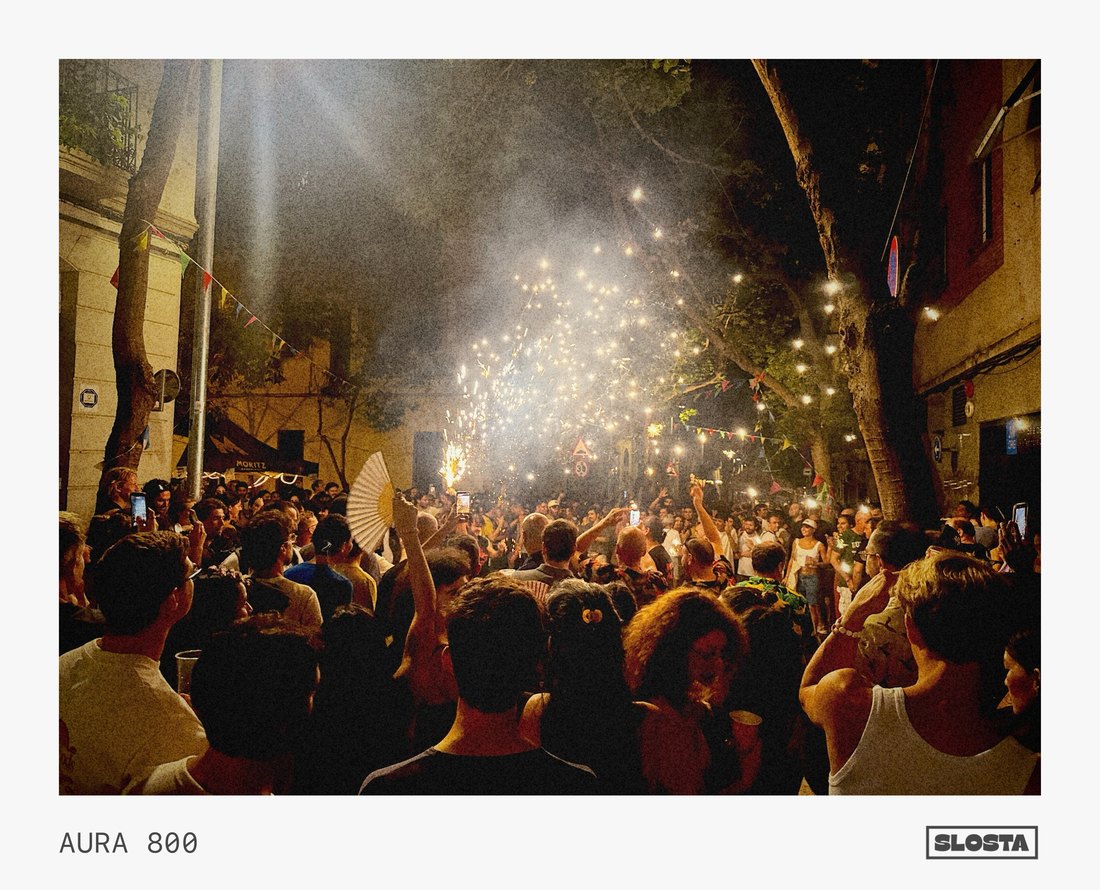 A dense crowd watching fireworks light up the night sky, framed with SloSta's AURA 800 film stock